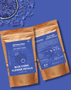 Two packages of Pahari Haat Blue Corn Flower Petals on a blue background with flower petals.
