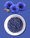 Blue cornflower flowers and dried flower petals in a white bowl on a blue background